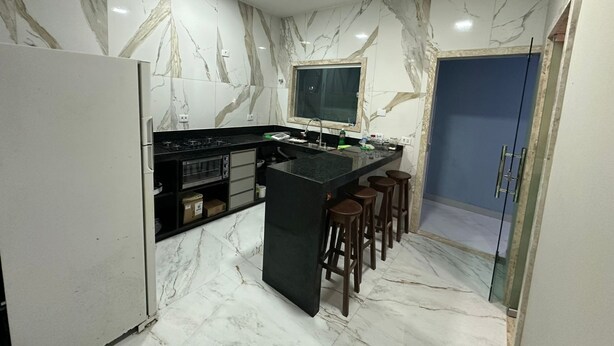 A modern kitchen with marble walls, a black countertop, and a built-in oven. - BEACH HOUSE (Prado)