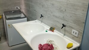 A bathroom with a white sink, a small mirror, and a towel rack. - BEACH HOUSE (Prado)
