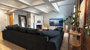 A modern living room with a dark grey sofa, a white fireplace, a flat-screen TV, and a brick wall. - Seafront lounge in the centre of Helsinki, Ideal for party and corporate events. (Helsinki)