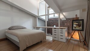 A bedroom with a bed, a desk, a dresser, and a painting on a tripod stand. - Seafront lounge in the centre of Helsinki, Ideal for party and corporate events. (Helsinki)