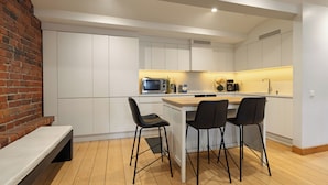 A modern kitchen with white cabinets, a wooden countertop, and black chairs. - Seafront lounge in the centre of Helsinki, Ideal for party and corporate events. (Helsinki)