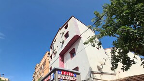 Ett hotell med en restaurang på bottenvåningen, en skylt och en parkerad bil.