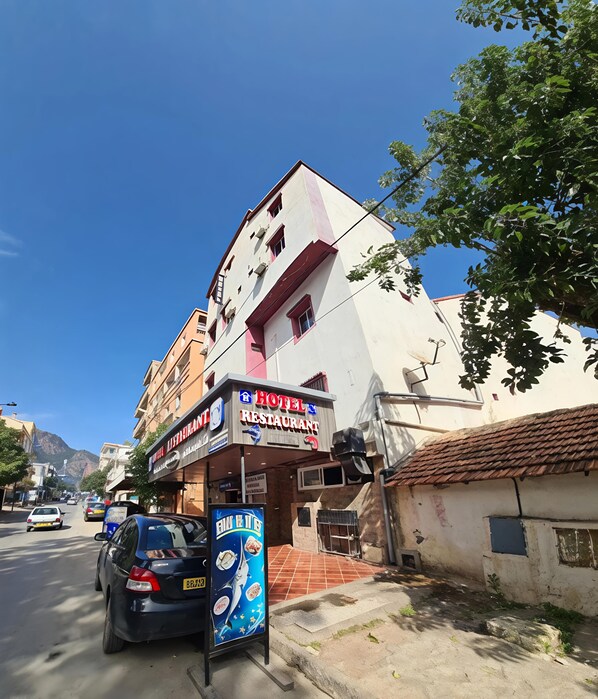 Un hotel con ristorante al piano terra, una targa e un'auto parcheggiata.