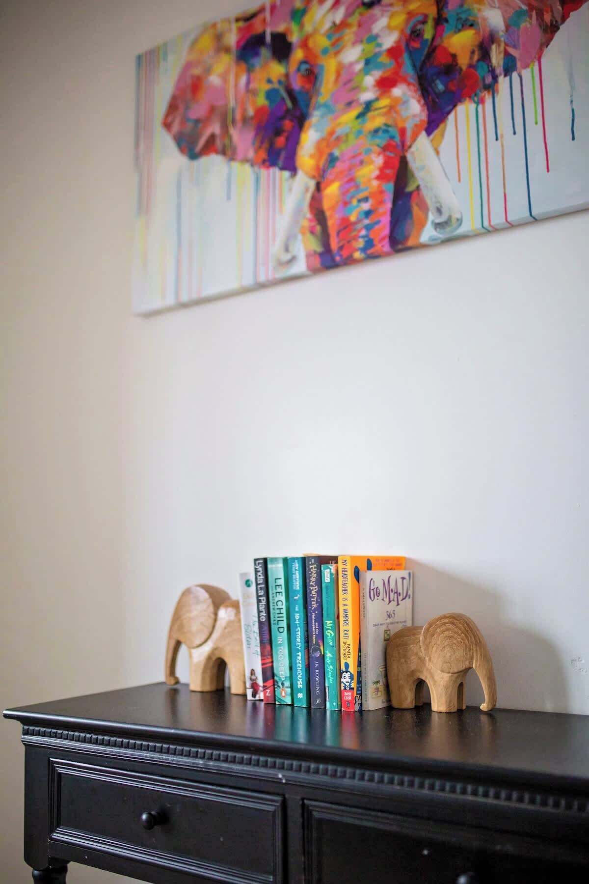 A bookshelf with books and wooden elephant figurines.