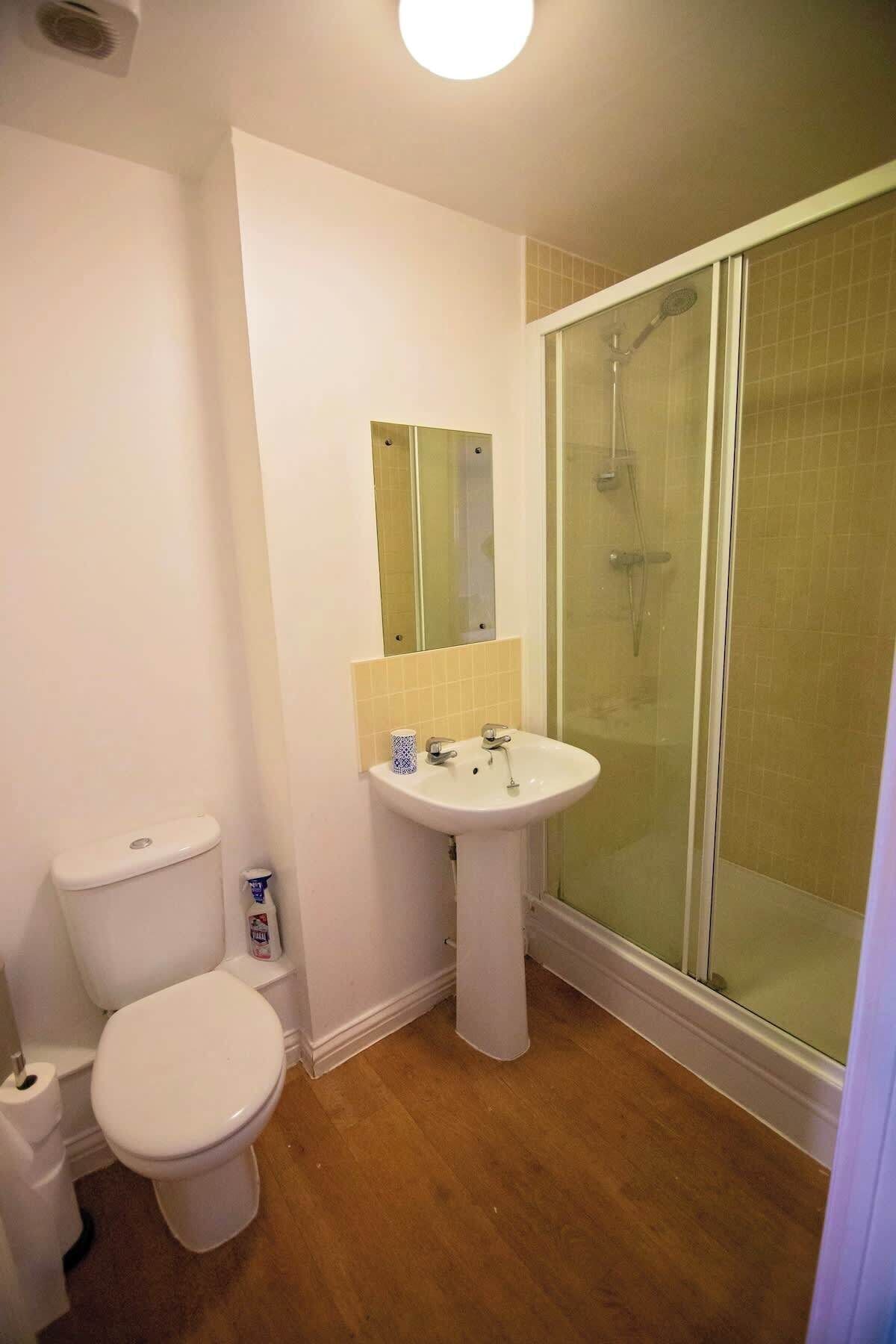 A bathroom with a toilet, sink, and glass-enclosed shower.