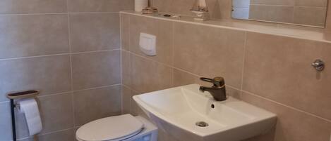 Ein Badezimmer mit Toilette, Waschbecken und Spiegel.