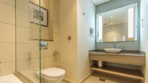 A modern bathroom with a glass-enclosed shower, a white toilet, a sink with a vessel basin, and a large mirror above the sink. - Spacious 1BR Rental | 1050 sq ft | Luxury Lifestyle in Paramount Towers (Dubai)