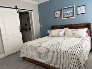 Ein Schlafzimmer mit einem Bett, einem Holzkopfende, einem Schminktisch und einer Tür mit Schiebetür.