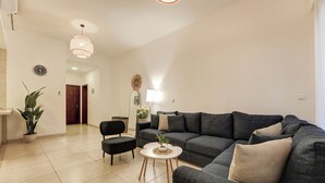 Un salon moderne avec un canapé gris, une table basse ronde et une plante en pot.