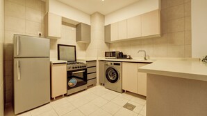 Una cocina compacta con refrigerador, horno, microondas y lavadora.