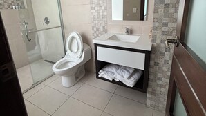 A modern bathroom with a glass shower enclosure, a toilet, a sink with a mirror, and a towel rack.
