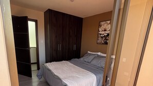 A bedroom with a bed, a wardrobe, and a door leading to another room.