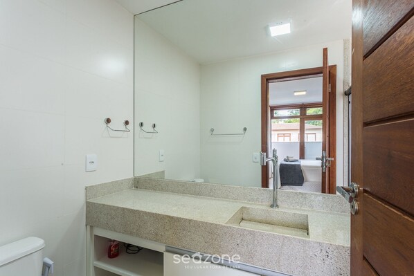 A bathroom with a large mirror, a sink, and a toilet.