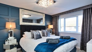 A neatly arranged bedroom with a large bed, two bedside tables, a mirror, and a window with curtains.
