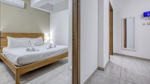 Une chambre d’hôtel avec un lit en bois, du linge de lit blanc, une lampe de chevet et un grand miroir au mur.