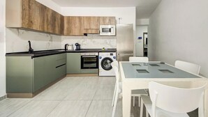 Une cuisine compacte équipée d’un lave-linge, d’un four à micro-ondes et d’un réfrigérateur.