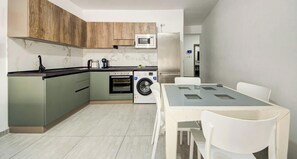 A compact kitchen with a washing machine, a microwave, and a refrigerator. - Paceville Energy Meets Comfort, 2BR Apt + Balcony! (St. Julian`s)