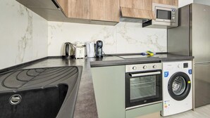 Une cuisine compacte équipée d’un four, d’un micro-ondes et d’un lave-linge intégrés.