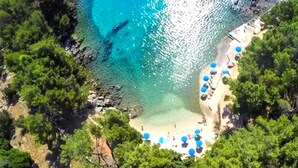 Une vue aérienne d’une plage aux eaux turquoise et limpides, bordée d’une végétation luxuriante.