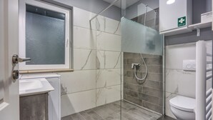 Une salle de bain moderne avec une douche à parois de verre, des toilettes et un lavabo.
