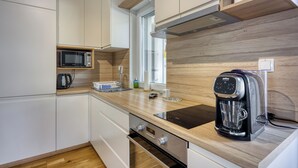 Une cuisine moderne avec des meubles blancs, un four à micro-ondes, une machine à café et des plans de travail en bois.