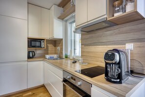 Een moderne keuken met witte kasten, een magnetron, een koffiezetapparaat en houten werkbladen.