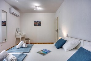 Habitación de hotel con una cama, una mesita de noche, un espejo, un escritorio con una silla y un aire acondicionado instalado en la pared.