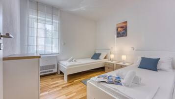 Una habitación de hotel con cama, mesitas de noche, un ventanal y una obra de arte colgada en la pared.