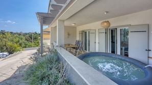 Ein Balkon mit Whirlpool, Sitzgelegenheit und Blick auf die umliegende Landschaft.