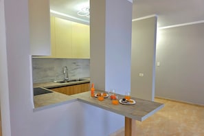 Una cocina moderna con encimera de mármol, pileta integrada y espacio para desayunar con jugo de naranja y pastelería.