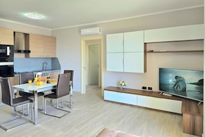A modern kitchen with a dining area, a TV, and a hallway. - Sea Vista Durres 50m From Beach (Durrës)