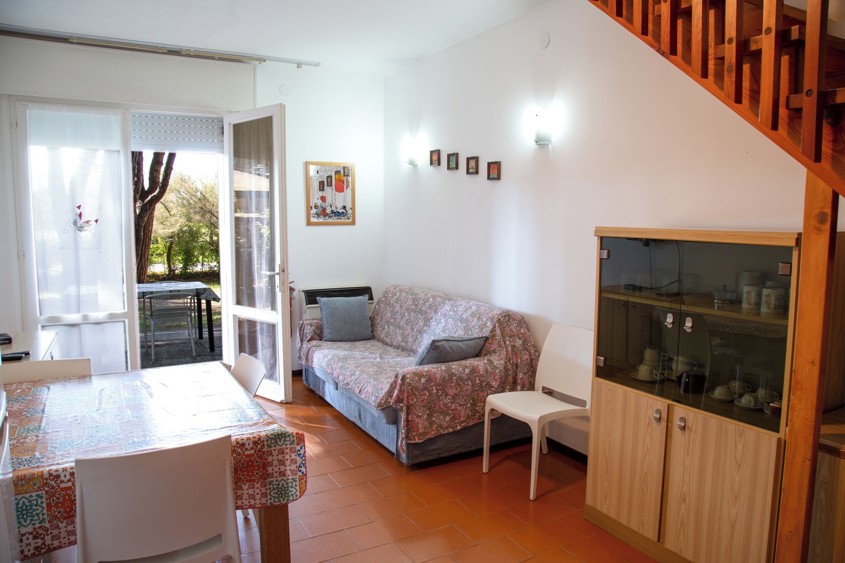 Uma sala de estar aconchegante com um sofá, uma mesa de jantar e um aparador de vidro.