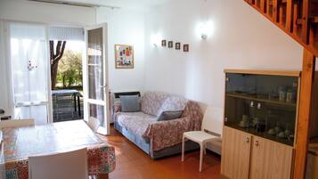 Uma sala de estar aconchegante com um sofá, uma mesa de jantar e um aparador de vidro.