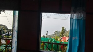 A view through a window with a green netting and a red roof structure in the background.