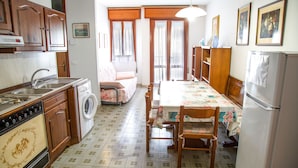 Una cocina con armarios de madera, lavadora, mesa de comedor con sillas y refrigerador.