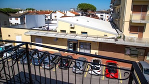 Un estacionamiento con varios autos, un edificio de techo plano y un árbol al fondo.
