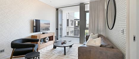 A modern living room with a sofa, a coffee table, a TV, and a patterned rug.
