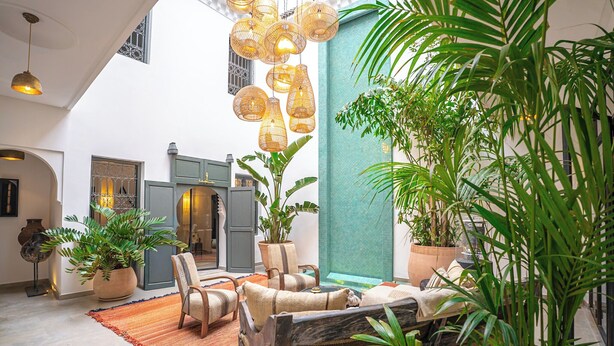 A spacious indoor area with a high ceiling, a seating area with a sofa and chairs, and a large potted plant. - Manzil Fanny Private Riad & Spa (Marrakech)