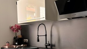 Une cuisine moderne avec un plan de travail noir, des meubles blancs, un four encastré et une hotte aspirante noire.