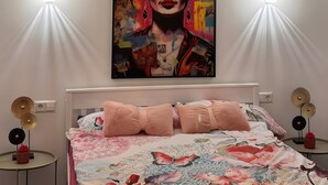 Une chambre à coucher avec un lit, un tableau accroché au mur, des lampes de chevet et un luminaire au plafond.