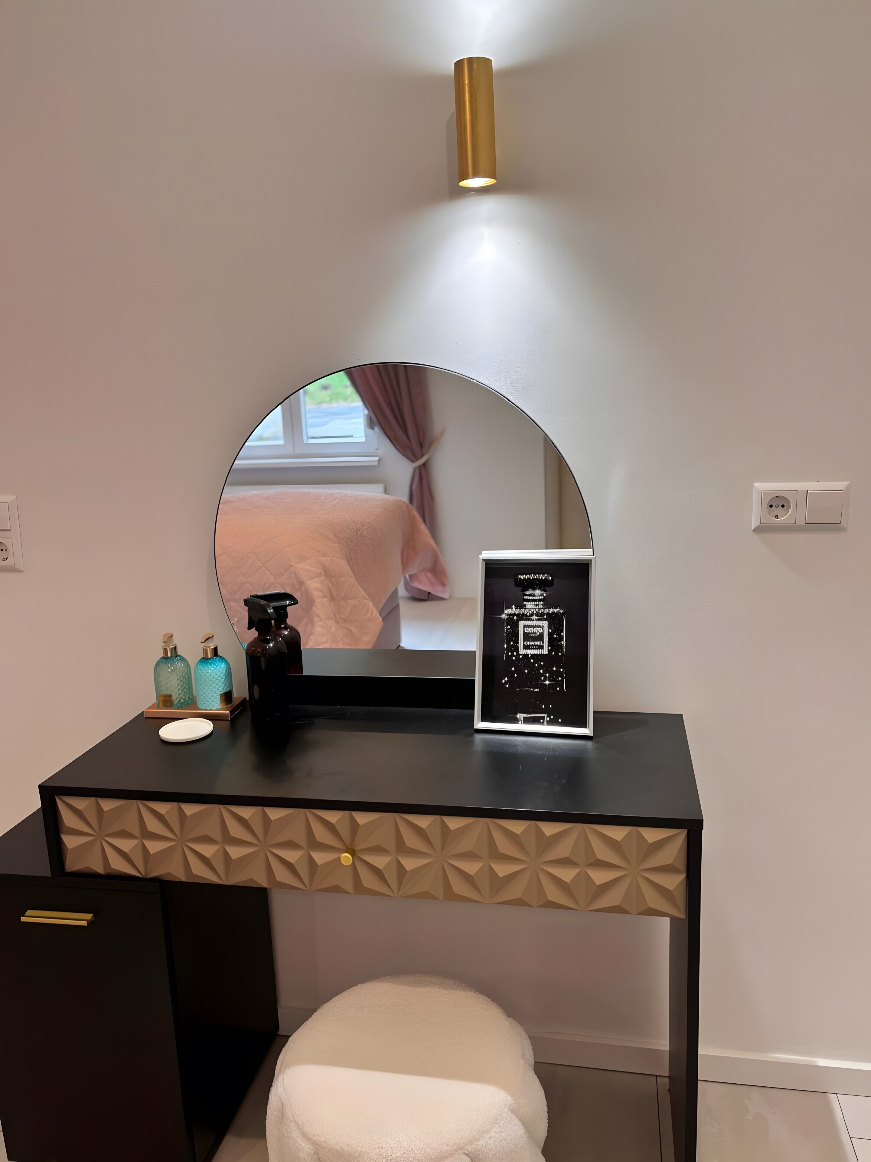 A vanity with a mirror, a framed perfume bottle, and toiletries.