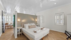 Ein geräumiges Schlafzimmer mit einem großen Bett, einem kleinen Nachttisch, einer Wandlampe und einem Fenster mit Rollläden.