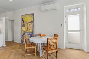A dining area with a round table, four wooden chairs, a bowl of oranges, and a large painting on the wall. - Keizershof, Otrobanda, Stylish Open-Concept Apt 25 (Willemstad)