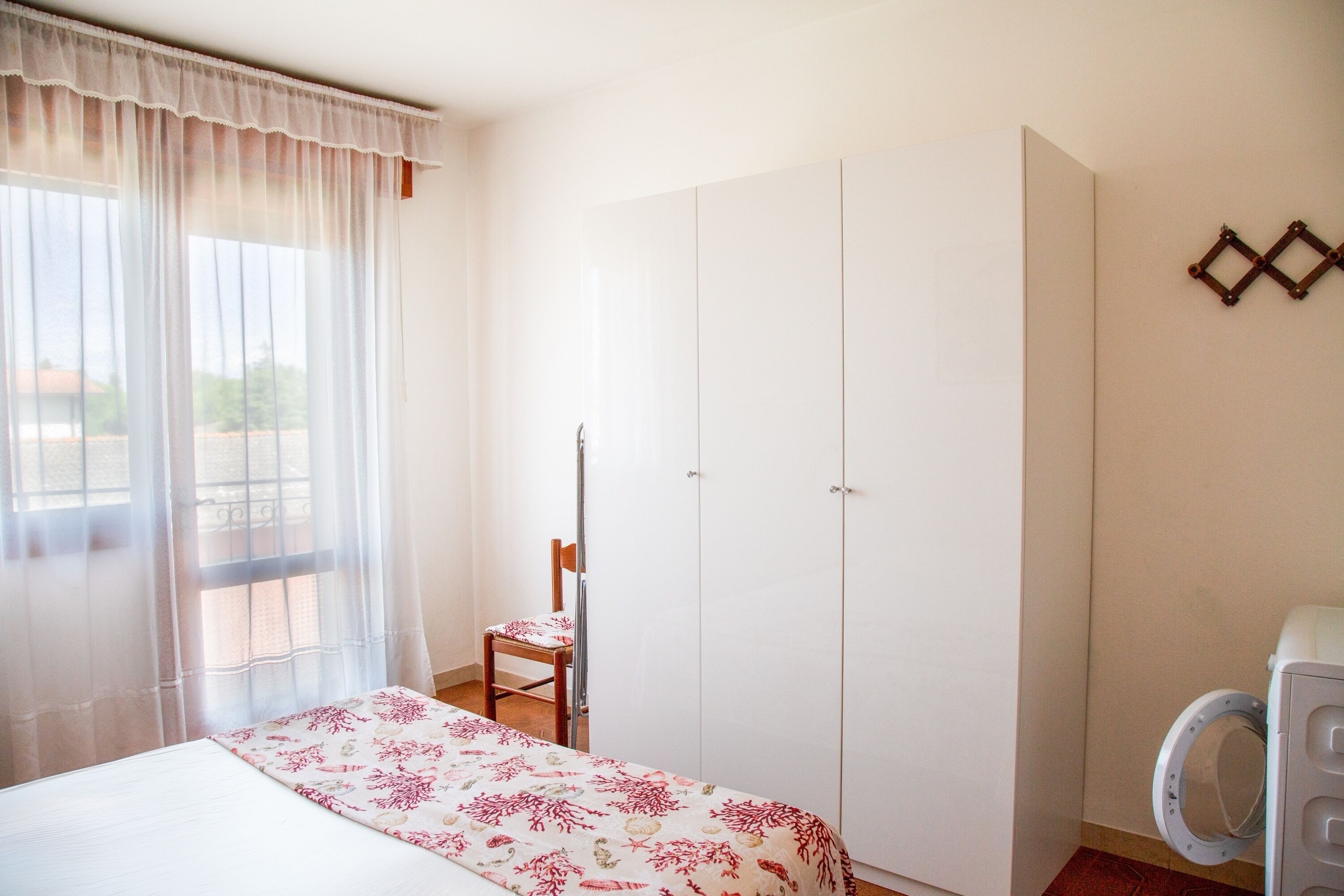 Ein Schlafzimmer mit Bett, Stuhl, Kleiderschrank und Waschmaschine.