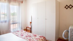 Une chambre à coucher comprenant un lit, une chaise, une armoire et un lave-linge.