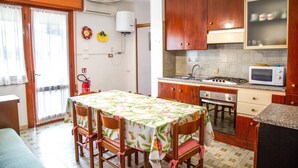 Une cuisine compacte dotée de meubles en bois, d’un four à micro-ondes, d’une cuisinière et d’un coin repas avec une table et des chaises.