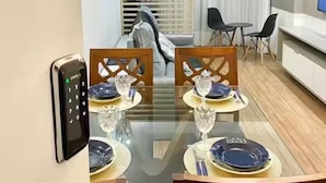 A modern dining area with a glass table, wooden chairs, and a built-in phone. - Pé na Areia Praia de Itaparica Espirito Santo, vista para o mar e piscina (Vila Velha)