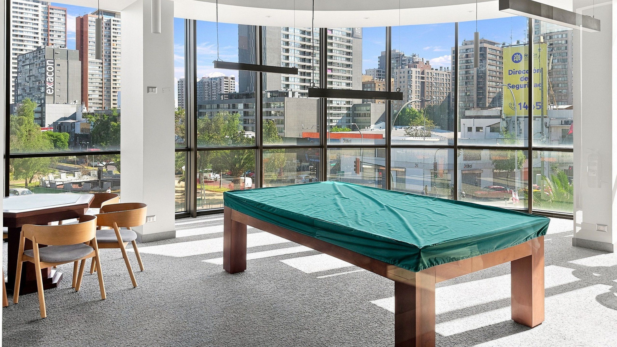 A pool table in a room with large windows overlooking a cityscape.