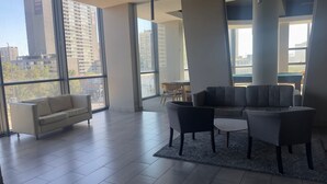 Un intérieur moderne avec un canapé, des fauteuils et une vue sur de hauts immeubles.