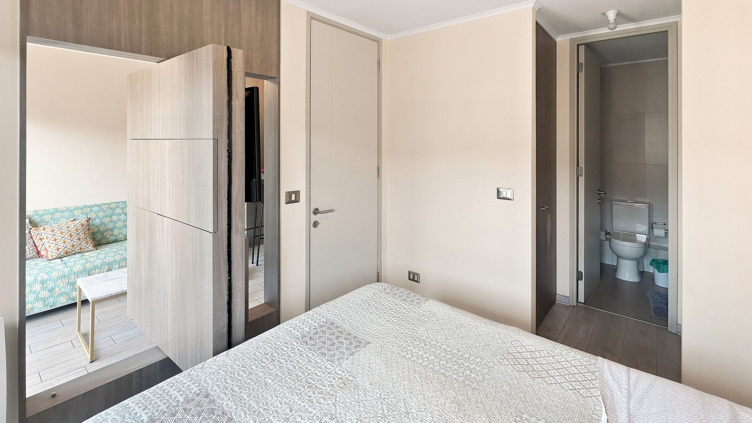A bedroom with a bed, a wardrobe, and a bathroom visible through an open door.